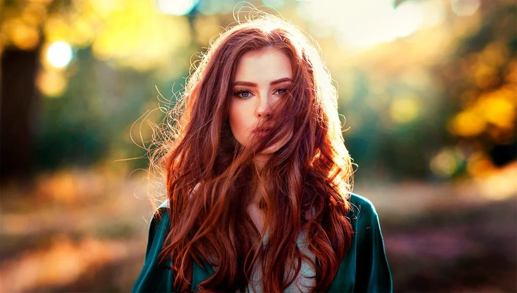 Red-haired woman photographed in golden autumn light