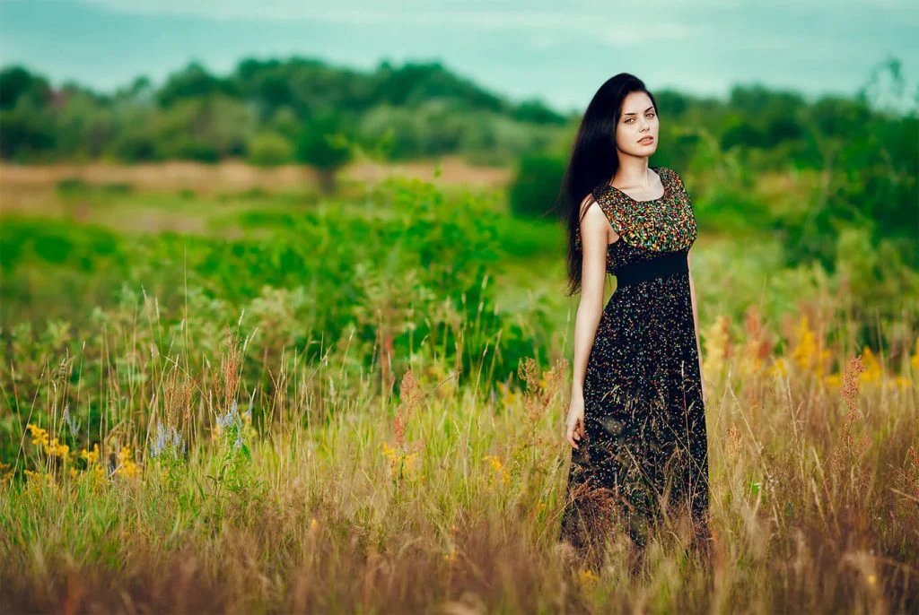 Woman in a black dress standing in a green meadow